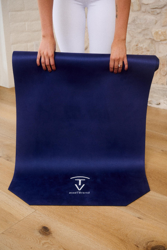 Woman unrolling a navy machine-washable yoga mat with non-slip microfiber surface indoors