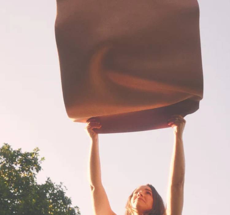 Woman lifting a microfiber surface Asset Mat upwards with a blurred background